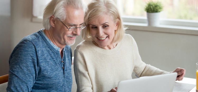 A mature couple looking at something together on a laptop.